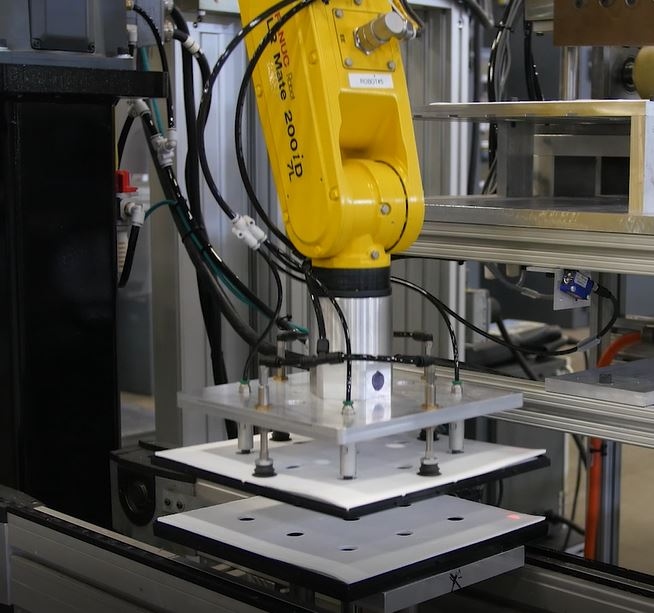 FANUC robotic arm placing pasted bipolar plates on assembly station
